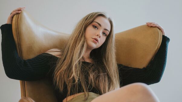 Beautiful Model Sitting On Sofa Looking At Viewer Wallpaper
