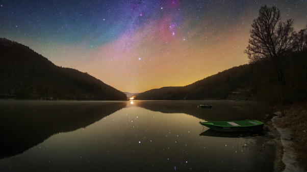 Boat Sitting On Top Of A Lake Under A Night Sky Wallpaper