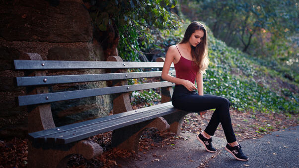 Girl Sitting On Bench Outdoors Wallpaper