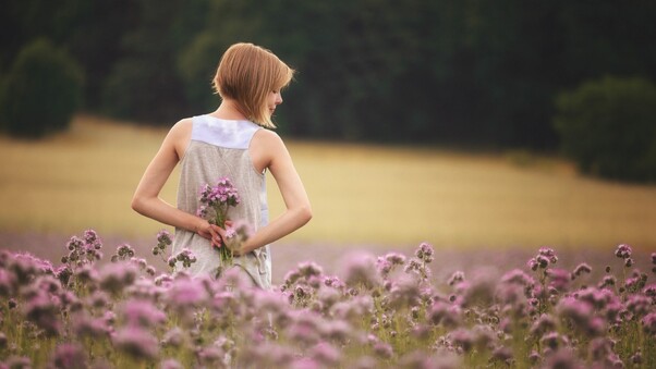 Girl With Flowers Standing In Field Wallpaper