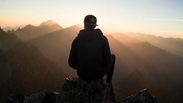 Man With Cap Sitting On The Mountain Edge Wallpaper