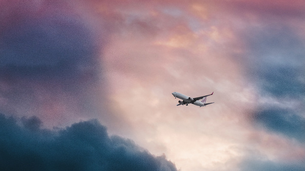 Passenger Plane In Clouds View From Far Away Wallpaper