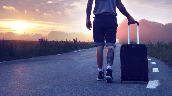 Person Walking On Road With Suitcase Wallpaper