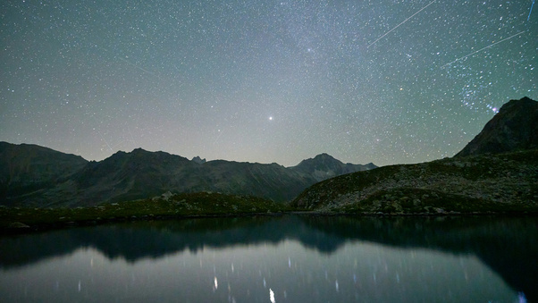 Starry Night Sky Over Calm Mountains Wallpaper