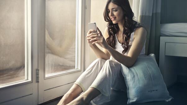 Woman Sitting Beside Window Holding Phone Wallpaper