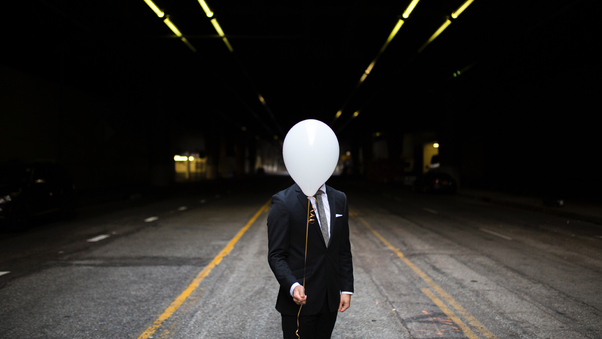 Young Man In Suit Holding Balloons In Front Of Face Wallpaper