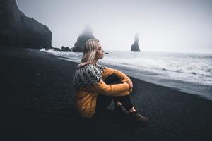 Girl In Sweater Sitting With Eyes Closed Sitting At Beach Wallpaper