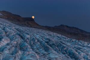 Moon Rising Over A Glacier With Mountains Wallpaper