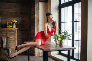 The Girl In The Red Dress Sitting On A Table Touching Flowers Wallpaper