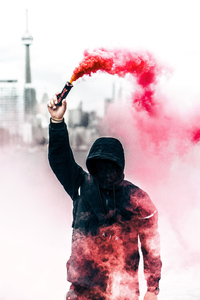A Person In A Hoodie With Smoke Grenade (320x480) Resolution Wallpaper