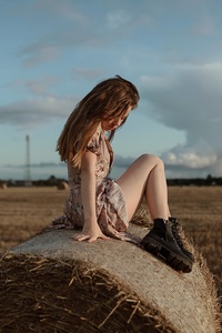 Girl Sitting On Straw Roll (1080x2160) Resolution Wallpaper