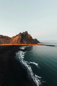 Waves Against The Ember Ridge (750x1334) Resolution Wallpaper