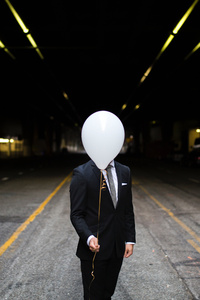Young Man In Suit Holding Balloons In Front Of Face (540x960) Resolution Wallpaper